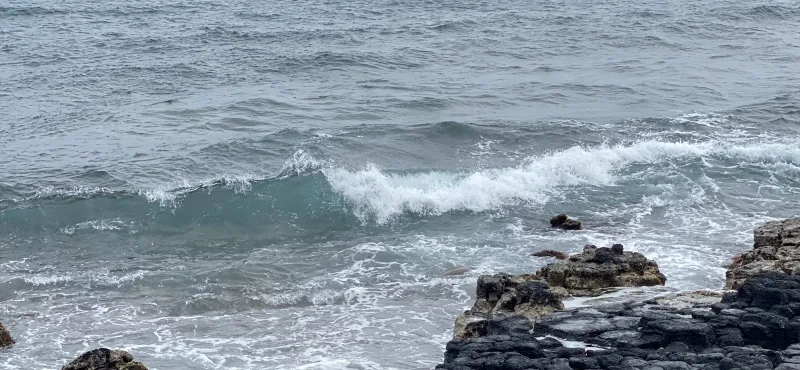 ocean waves cresting with rock formations in foreground